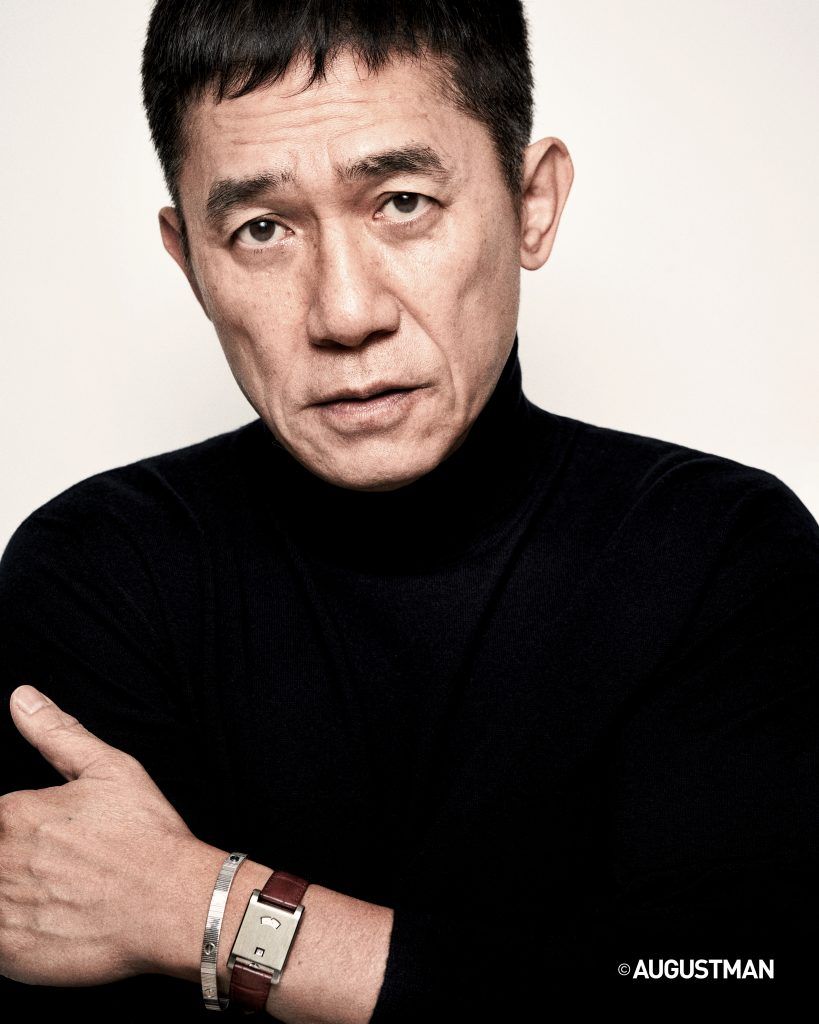 Tony Leung is wearing a turtleneck pullover from Ralph Lauren Purple Label, and a LOVE Unlimited bracelet in white gold and Tank a Guichet in platinum, from Cartier.