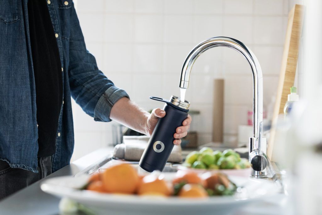 A person filling a bottle of water to drink as a method to reduce hypertension